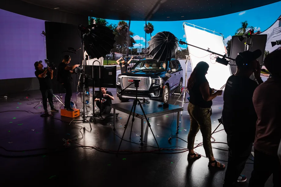 Full production set with lighting rigs and cinema cameras shooting a vehicle on an LED stage