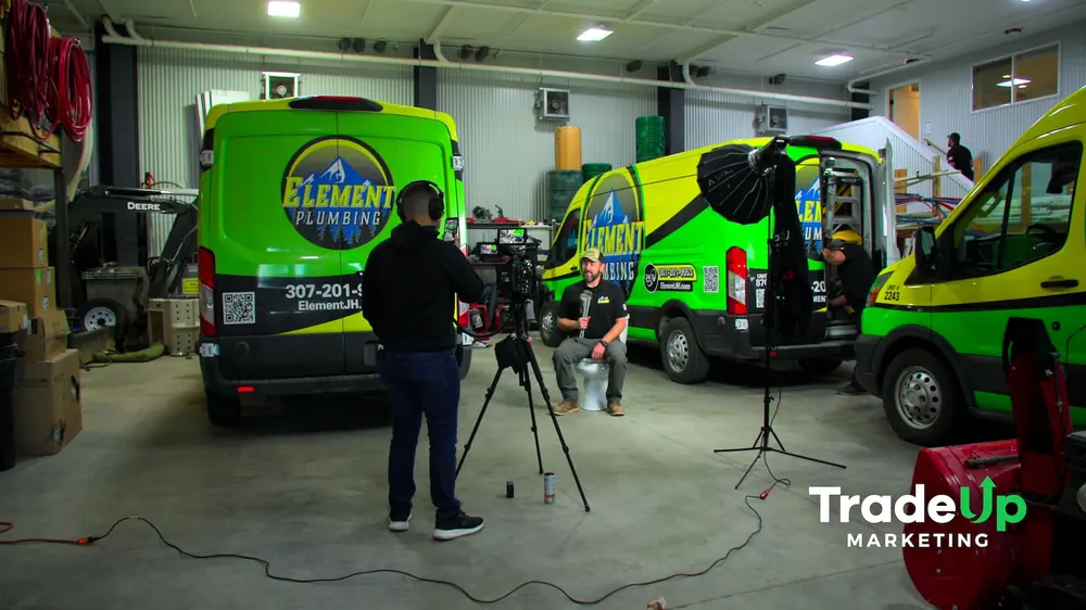 Filming an Element Plumbing technician seated among lime-green service vans in the shop