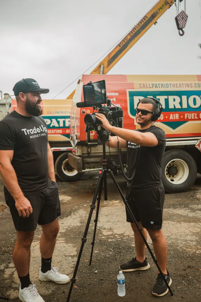 Jordan Lung and a TradeUp camera operator setting a shot in front of a Patriot Heating fuel truck