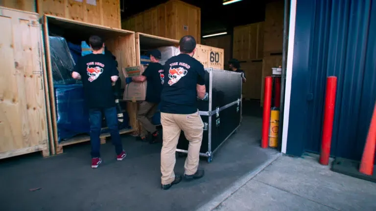 Immediate Movers project photo — the crew easing a road case into a timber storage vault inside the warehouse